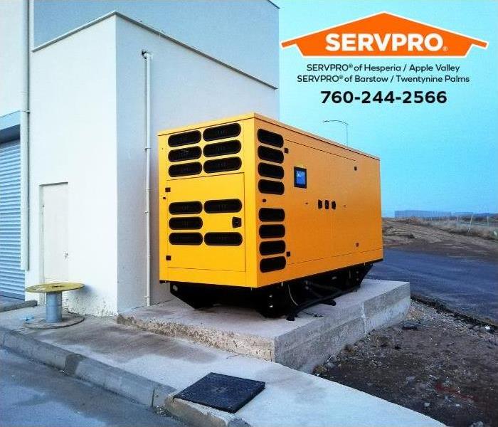 A diesel, electric power generator is mounted next to a building.